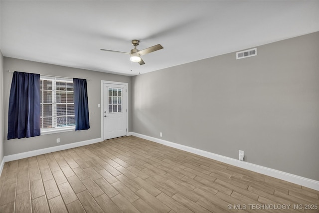 empty room with baseboards, ceiling fan, visible vents, and wood finished floors