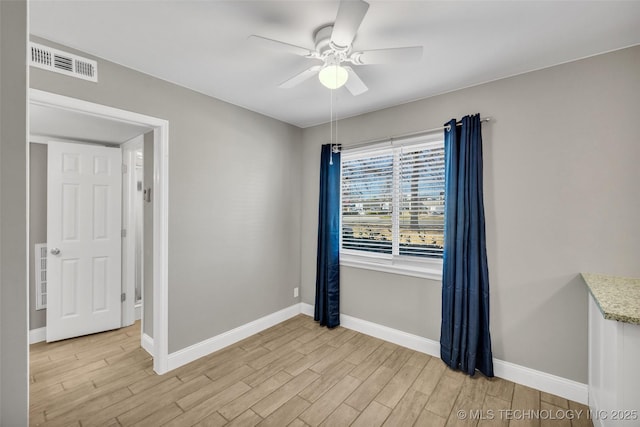 spare room featuring light wood-style floors, baseboards, visible vents, and ceiling fan