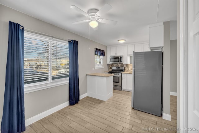 kitchen featuring tasteful backsplash, white cabinetry, stainless steel appliances, and light wood-style flooring