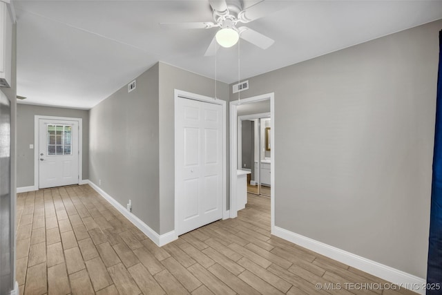 interior space with light wood finished floors, a ceiling fan, visible vents, and baseboards