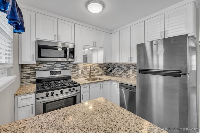 kitchen featuring tasteful backsplash, white cabinetry, stainless steel appliances, and a sink