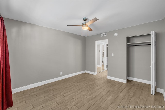 unfurnished bedroom featuring baseboards, visible vents, ceiling fan, wood finished floors, and a closet