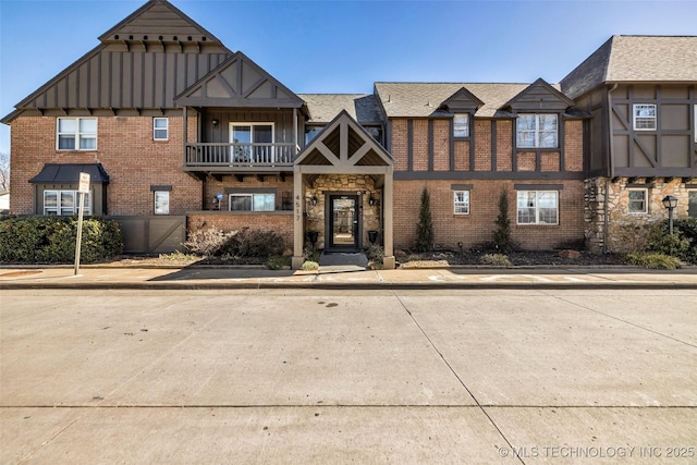 view of front of property featuring stone siding, brick siding, board and batten siding, and a balcony