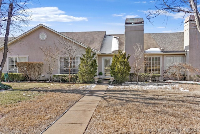 view of front facade with a front lawn, a chimney, and stucco siding