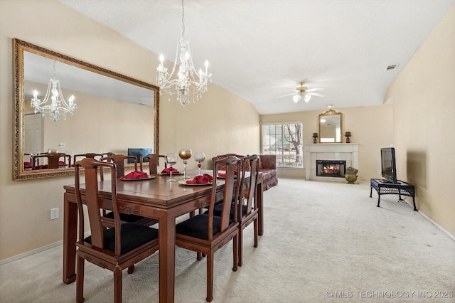 dining area featuring light colored carpet, visible vents, a tile fireplace, and ceiling fan with notable chandelier