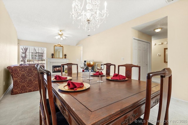 dining room with light carpet, a warm lit fireplace, baseboards, a textured ceiling, and ceiling fan with notable chandelier