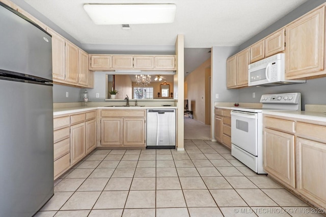 kitchen with light tile patterned floors, a sink, light countertops, appliances with stainless steel finishes, and light brown cabinetry