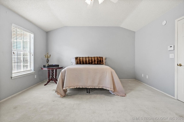 bedroom featuring vaulted ceiling, a textured ceiling, carpet flooring, and a ceiling fan