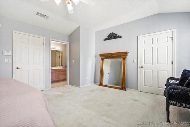 bedroom with visible vents, connected bathroom, light colored carpet, lofted ceiling, and ceiling fan