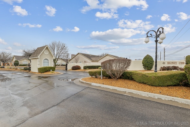 view of street with curbs, street lighting, a gated entry, and a gate