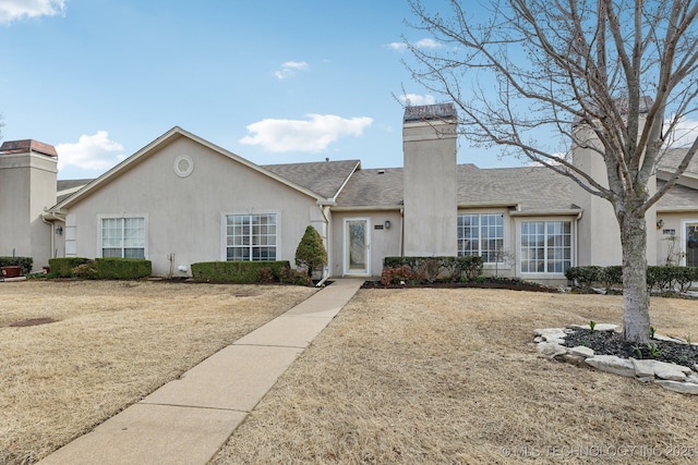 view of front of property featuring roof with shingles, a chimney, and stucco siding