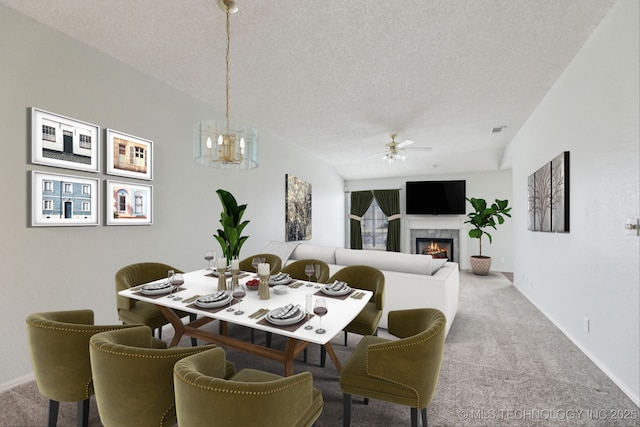 carpeted dining area with baseboards, visible vents, a high end fireplace, a textured ceiling, and ceiling fan with notable chandelier