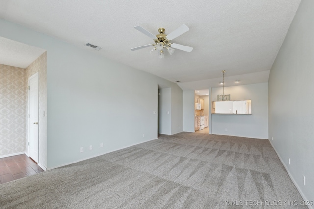 unfurnished living room featuring wallpapered walls, ceiling fan, visible vents, and a textured ceiling