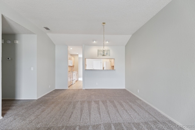 unfurnished living room featuring baseboards, visible vents, light colored carpet, a textured ceiling, and a notable chandelier