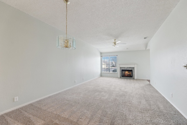 unfurnished living room featuring carpet, visible vents, a premium fireplace, a textured ceiling, and ceiling fan with notable chandelier