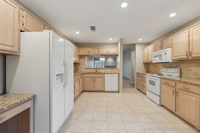 kitchen with light brown cabinetry, white appliances, a sink, and visible vents