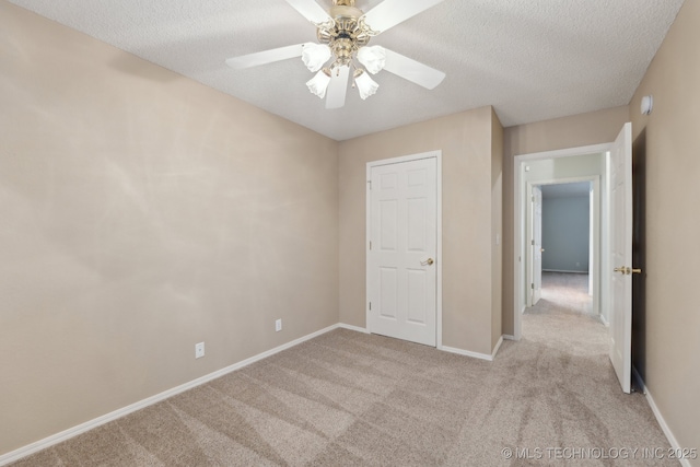 unfurnished bedroom featuring light carpet, a textured ceiling, and baseboards