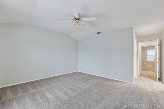 carpeted empty room with lofted ceiling, ceiling fan, visible vents, and baseboards