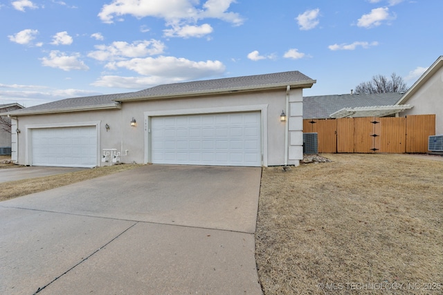 garage featuring central air condition unit, a gate, fence, and concrete driveway