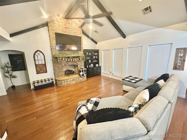 living area featuring a ceiling fan, visible vents, a fireplace, and wood finished floors