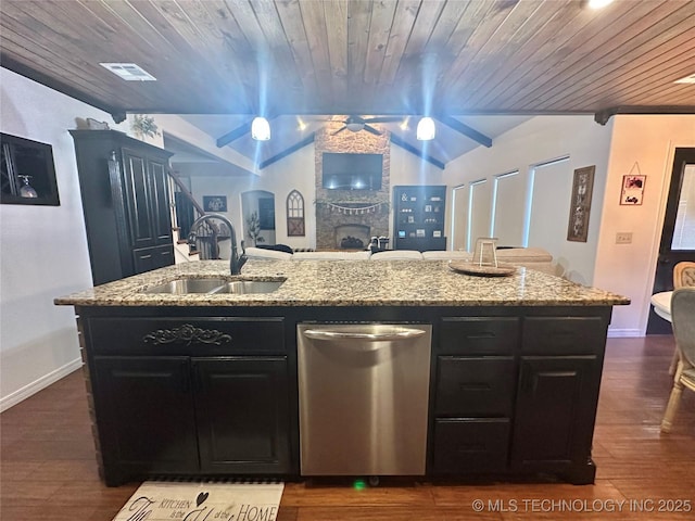 kitchen with light stone counters, stainless steel dishwasher, a sink, and a kitchen island with sink