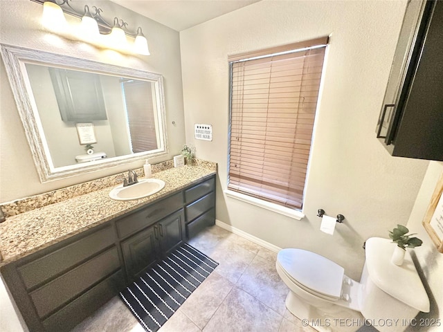 bathroom with toilet, tile patterned flooring, baseboards, and vanity