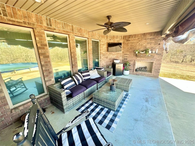 view of patio with an outdoor living space with a fireplace and a ceiling fan