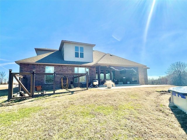 back of house featuring a patio, brick siding, and a lawn