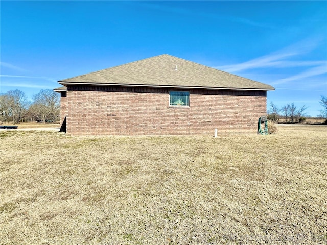 view of property exterior featuring brick siding, a lawn, and roof with shingles