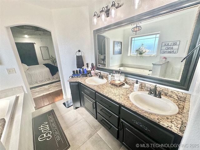 bathroom with ensuite bathroom, double vanity, a sink, and a garden tub