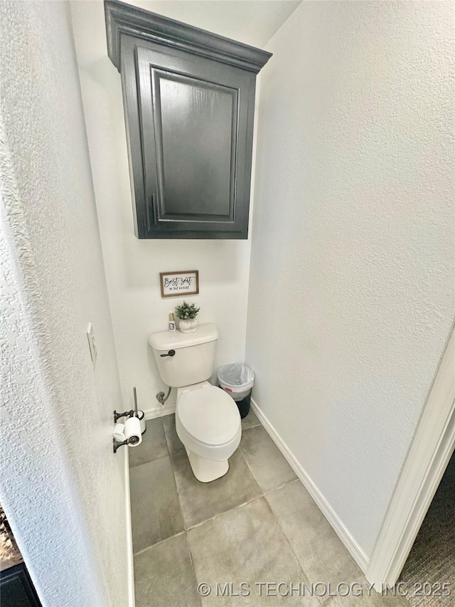 bathroom with toilet, baseboards, and tile patterned floors