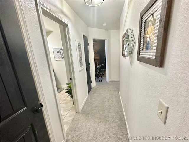 hall featuring light carpet and baseboards