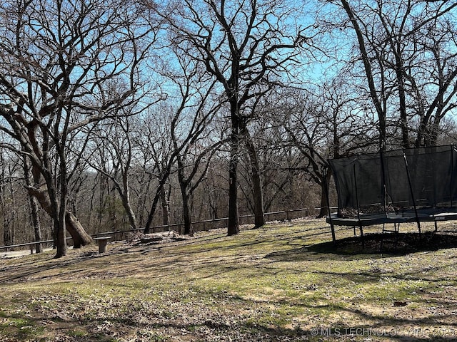 view of yard with a trampoline and fence