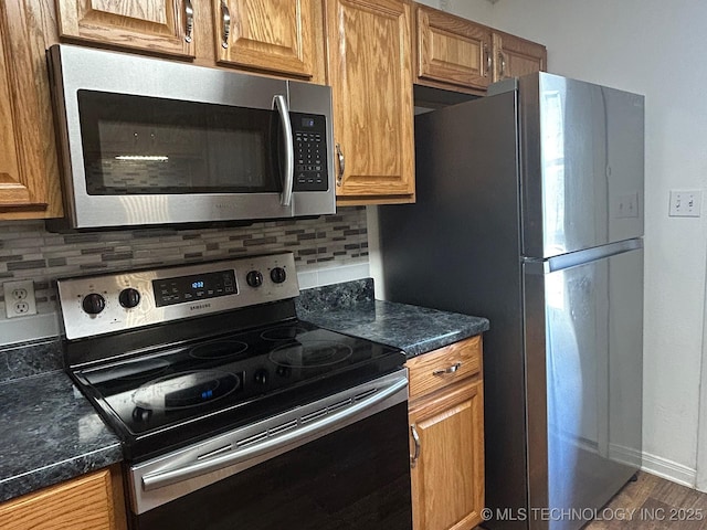 kitchen featuring dark countertops, tasteful backsplash, appliances with stainless steel finishes, and brown cabinets