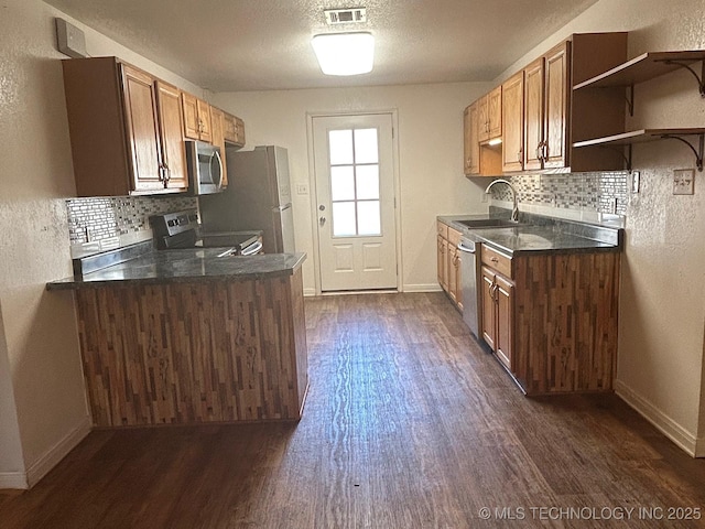 kitchen featuring visible vents, dark wood finished floors, dark countertops, appliances with stainless steel finishes, and a sink