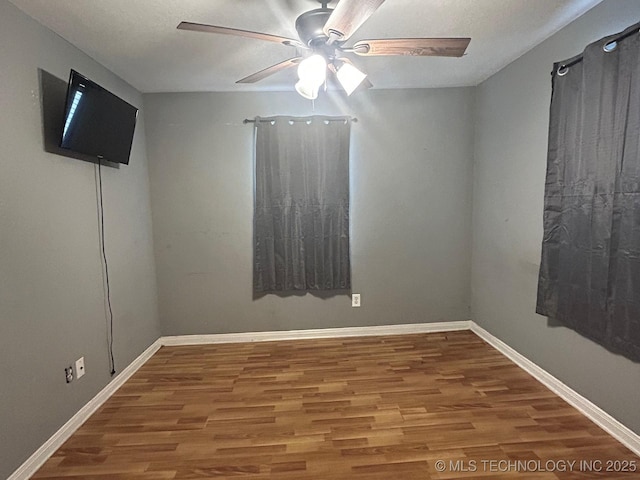 unfurnished room with ceiling fan, wood finished floors, and baseboards