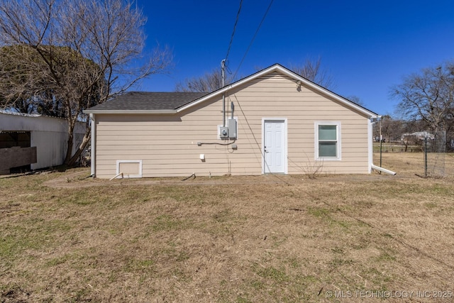 rear view of house with a shingled roof and a yard