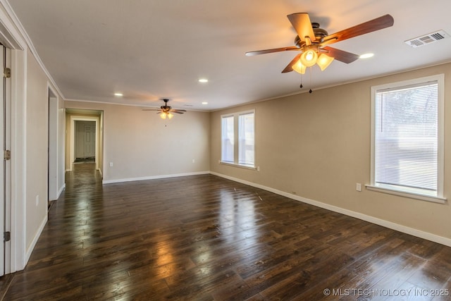 empty room featuring dark wood-style floors, baseboards, visible vents, and ornamental molding