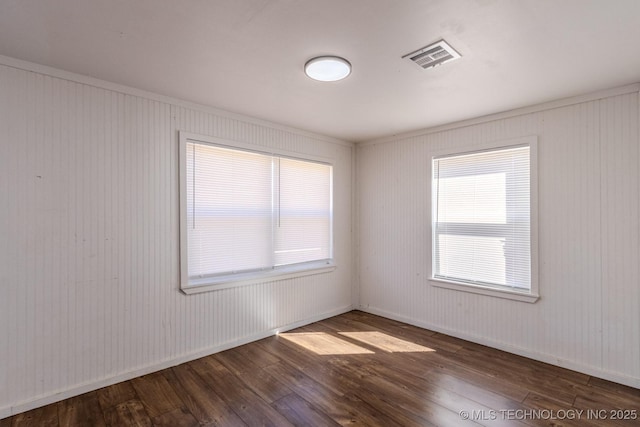 unfurnished room with hardwood / wood-style floors, visible vents, and baseboards