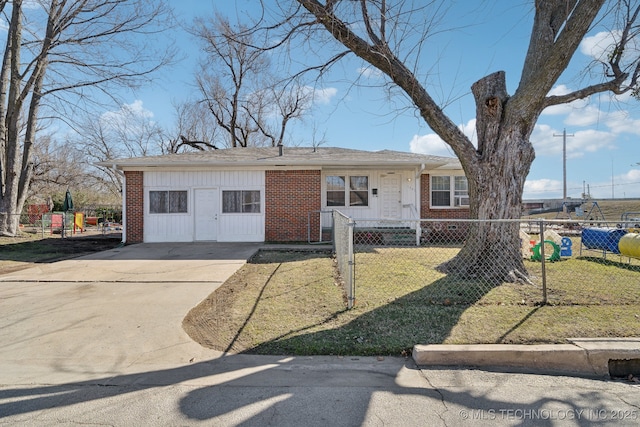 ranch-style home featuring concrete driveway, brick siding, a fenced front yard, and a front yard