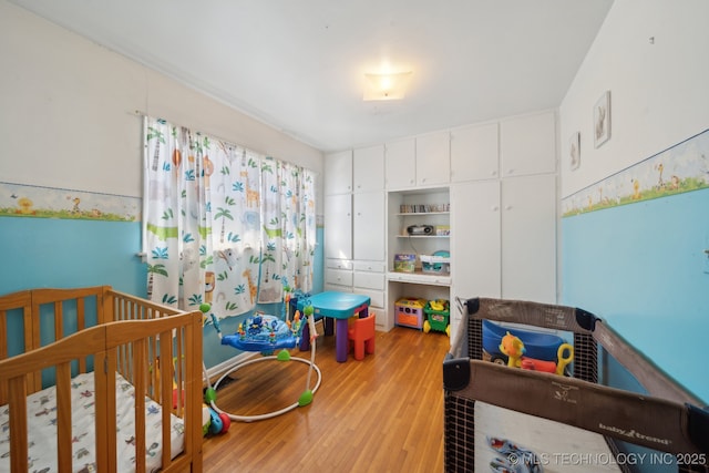 bedroom featuring a crib and light wood-style floors