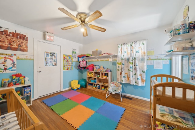 rec room with wood finished floors, a ceiling fan, and baseboards