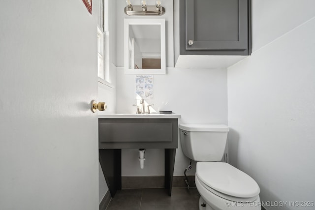 bathroom featuring toilet, tile patterned flooring, baseboards, and a sink