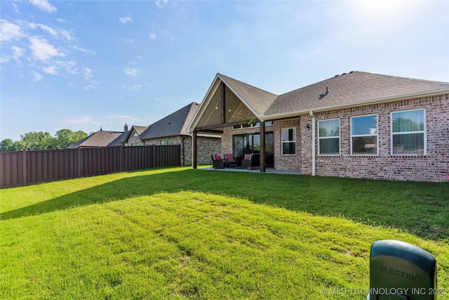 back of property featuring a yard, fence, a patio, and brick siding