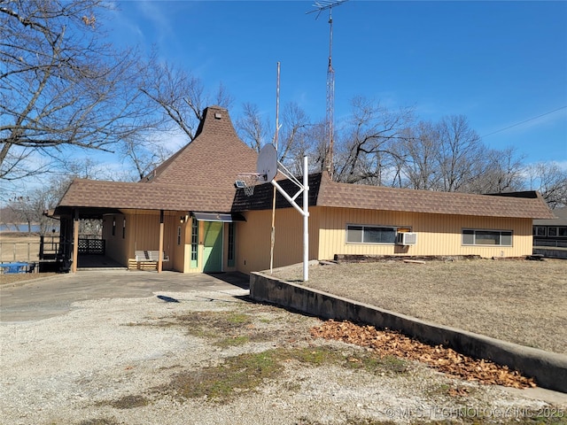 exterior space featuring driveway, a carport, and roof with shingles