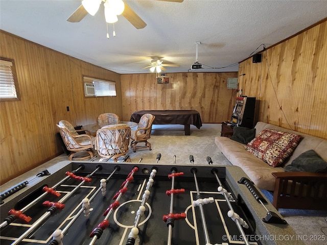 playroom with wood walls, ceiling fan, a textured ceiling, and carpet flooring