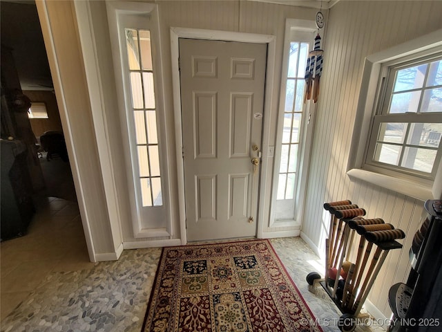 tiled foyer entrance with wood walls and baseboards