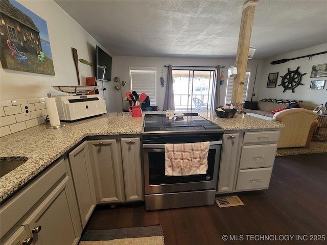 kitchen featuring light stone counters, dark wood finished floors, electric range, open floor plan, and a peninsula