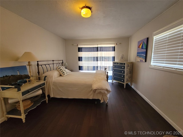 bedroom with dark wood-style floors, multiple windows, and baseboards