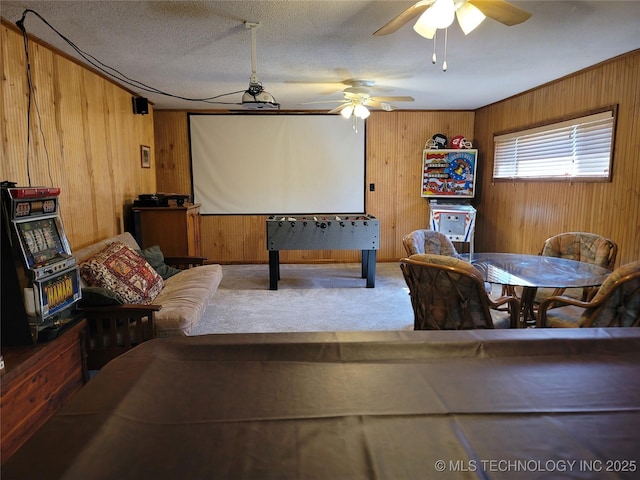 game room with ceiling fan, wood walls, and carpet flooring